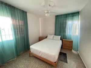 a bedroom with a white bed and green curtains at Apartamento calido in Santo Domingo