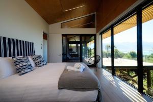 1 dormitorio con 1 cama grande y ventanas grandes en On The Edge, en Kaikoura