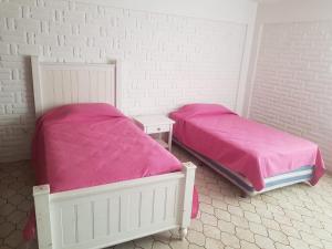 two beds in a room with pink sheets at Casa Cuernavaca con alberca en fraccionamiento in Cuernavaca