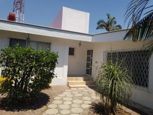 a white house with a gate and a palm tree at Casa Cuernavaca con alberca en fraccionamiento in Cuernavaca