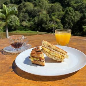 a white plate with a sandwich and a glass of orange juice at Espaço Canto in Santo Antônio do Pinhal