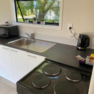 a kitchen with a stove top oven next to a sink at Tiny Home Farm Stay Retreat in Hikutaia