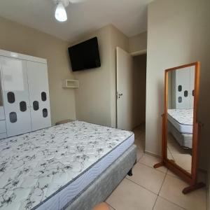 a bedroom with a bed and a mirror and a television at 4 ESTAÇÕES - apto em condomínio - 2 quartos com ar condicionado in Campo Grande