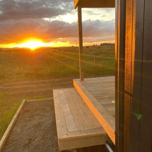 a wooden porch with the sunset in the background at Tiny Home Farm Stay Retreat in Hikutaia