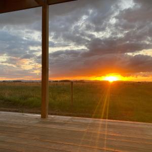 a sunset in a field with the sun setting at Tiny Home Farm Stay Retreat in Hikutaia