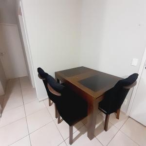 a wooden table with black chairs in a room at 4 ESTAÇÕES - apto em condomínio - 2 quartos com ar condicionado in Campo Grande