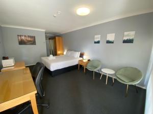 a hotel room with a bed and some chairs at Old Maitland Inn in Maitland