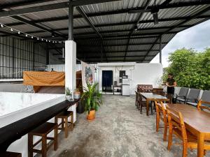 un patio esterno con tavoli e sedie in legno di Norm Space Hostel NST a Nakhon Si Thammarat