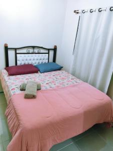 a bed with a pink comforter and two towels on it at Casa Excelente Localização! in Rio Grande