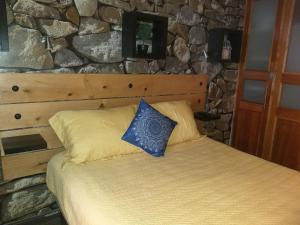 a bed in a room with a stone wall at Hostal La Casa del Puente in Santiago