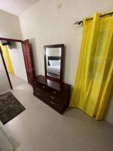 a bedroom with a mirror and a dresser and yellow curtains at Hagley Park Villa 
