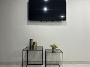 two tables with a television on a white wall at Suites Marvento in Ensenada