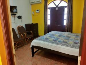 1 Schlafzimmer mit einem Bett, 2 Stühlen und einem Fenster in der Unterkunft Alexmarie Guest house 5 min to candolim Beach in Aguada