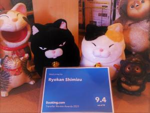 a group of toy cats sitting next to a sign at Ryokan Shimizu in Kyoto