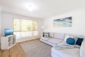 a white living room with a couch and a window at Driftwood Cottage 1 28 Farm Rd pet friendly Wi Fi Air Con and ground floor in Fingal Bay
