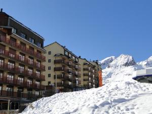 un bâtiment dans la neige à côté d'une montagne dans l'établissement LCB Apartaments Pas de la Casa, au Pas de la Case