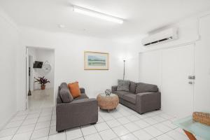 uma sala de estar com duas cadeiras e um sofá em Belle Escapes Under the Mango Tree Holiday Home em Trinity Beach