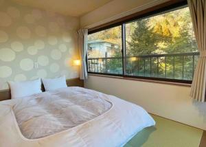 雅・小涌谷　温泉別荘　Miyabi Kowakudani Hopspring Villa في Ashinoyu: غرفة نوم بسرير كبير ونافذة كبيرة