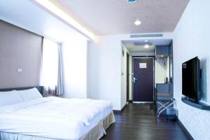 a bedroom with a large bed and a flat screen tv at West Hotel Puli in Puli