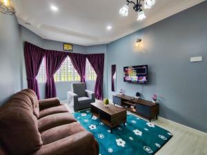 a living room with a couch and a tv at A ONE Holiday Apartment in Tanah Rata