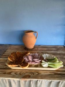 a plate of food on a wooden table with a vase at Cumpana Camping in Băile Olăneşti