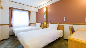 a hotel room with two beds and a desk at Toyoko Inn Kyoto Gojo-karasuma in Kyoto