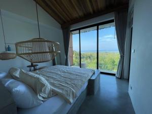 a bedroom with a bed and a large window at Villa Nour - 3 BR sea view pool villa in Srithanu in Srithanu