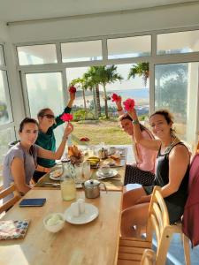 a group of people sitting at a table holding up flowers at La Terrasse in Rodrigues Island