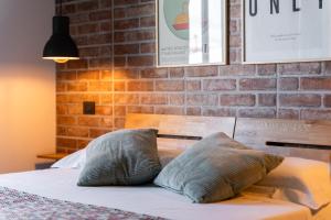 a bed with two pillows on it with a brick wall at Old Rooms in Quartu SantʼElena