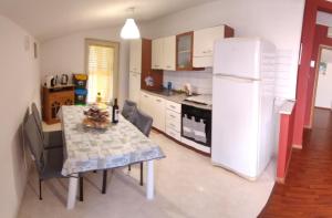 una cucina con tavolo e frigorifero bianco di Appartamento Tramonto Rosso a Catania
