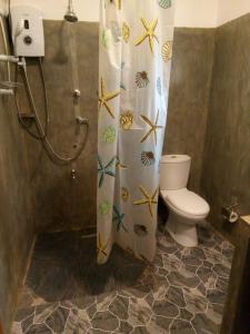 a bathroom with a shower curtain with a toilet at Sisila Villa in Bentota