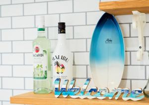 una mensola con due bottiglie di vino e una tavola da surf di Villa Malibu Palm Springs Miyakojima Resort a Miyakojima