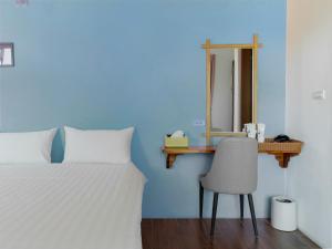 a bedroom with a bed and a mirror and a chair at 25Inn Hengchun Kenting in Nanwan
