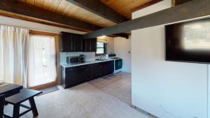 a kitchen with black cabinets and a flat screen tv at Aspen Hollow In The Upper Valley With High Speed Wifi in Red River