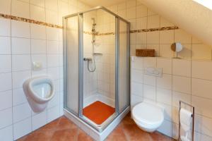 a bathroom with a shower and a toilet and a urinal at Ferienhaus Sabine Norddeich in Norddeich +22 photos