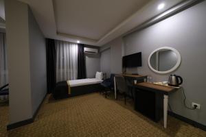 Habitación de hotel con cama, escritorio y espejo. en Eniza Hotel en Mersin
