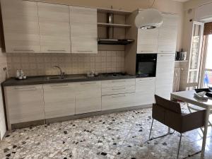 a kitchen with white cabinets and a table and a chair at house green station in Bari