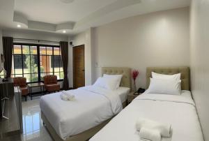 CottagePine Rayong Resort&Cafe في Ban Ko Kloi: غرفة نوم بسريرين وصالة جلوس