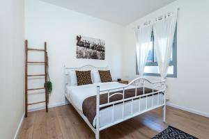 een witte slaapkamer met een wit bed en een ladder bij Melony Apartments Yam Suf Street in Eilat