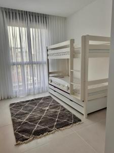 Dieses weiße Zimmer verfügt über ein großes Fenster und einen Teppich. in der Unterkunft Savyon View Tower - 2BR apartment in Jerusalem