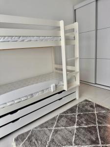 ein weißes Etagenbett in einem Zimmer mit einem Teppich in der Unterkunft Savyon View Tower - 2BR apartment in Jerusalem