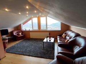 sala de estar con muebles de cuero y ventana grande en Casa La Munte - Zona Rucar en Cetatenii