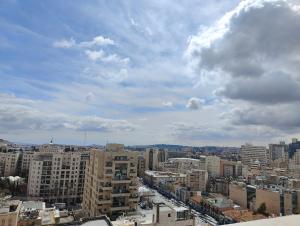Blick auf eine Stadt mit Gebäuden und einem wolkigen Himmel in der Unterkunft Savyon View Tower - 2BR apartment in Jerusalem