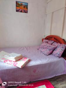 a bed with purple sheets and pillows on it at Myrol Homestay Kuala Ketil in Kuala Ketil