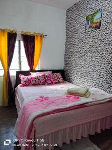 a bedroom with a bed with pink sheets and flowers at Myrol Homestay Kuala Ketil in Kuala Ketil