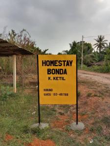 a yellow sign on the side of a road at Myrol Homestay Kuala Ketil in Kuala Ketil