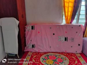 a small bed with a pink head board with flowers at Myrol Homestay Kuala Ketil in Kuala Ketil