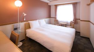 日立市にある東横INN日立駅前の白いベッドと窓が備わるホテルルームです。