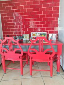 a red table and two chairs in front of a red brick wall at Cobra Self-Catering Guesthouse in Citrusdal