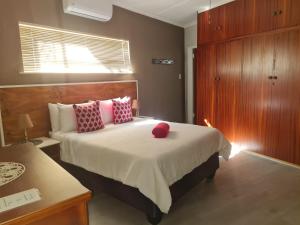 - une chambre avec un grand lit et des oreillers rouges dans l'établissement Cobra Self-Catering Guesthouse, à Citrusdal